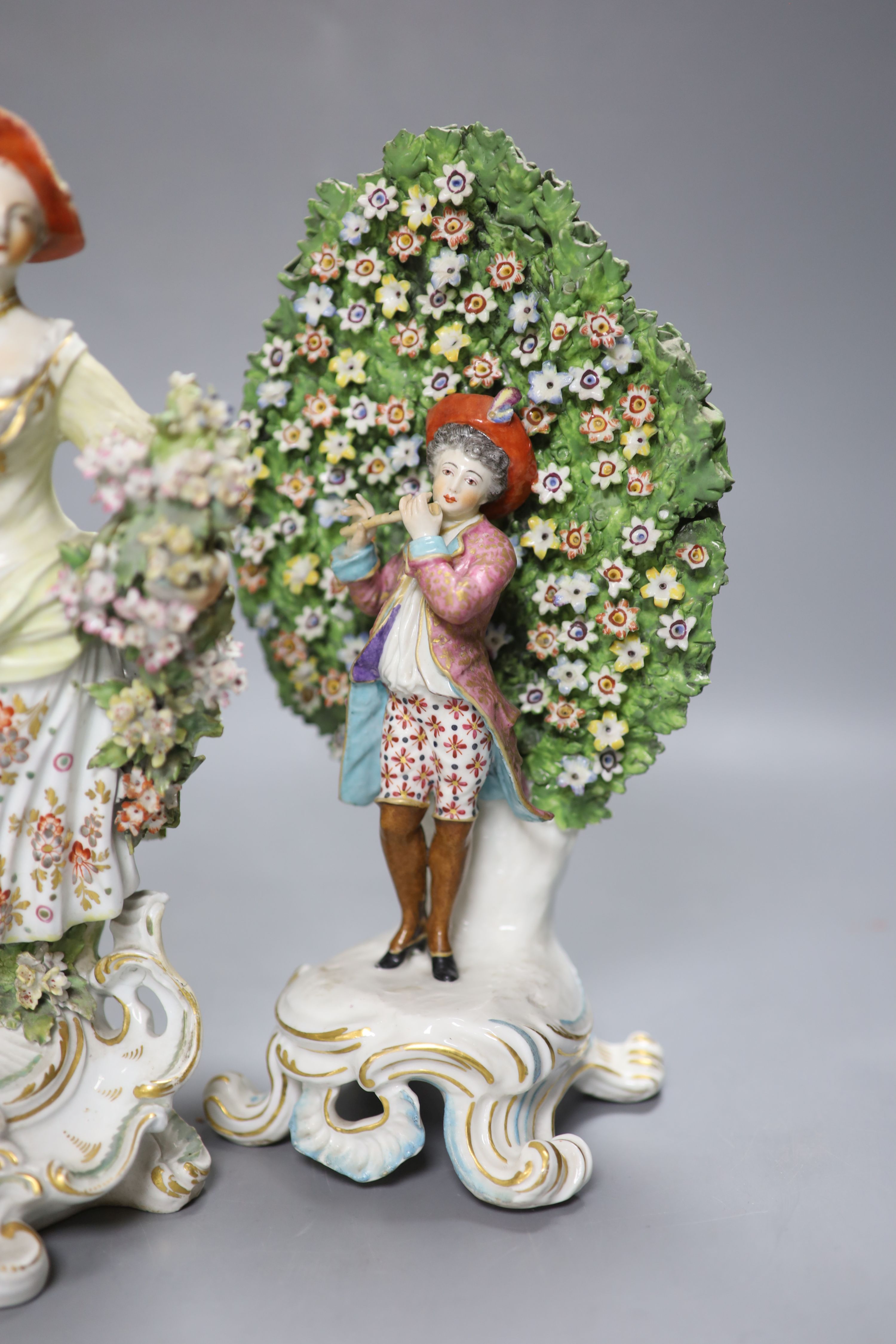 An 18th century Derby figure of a flower seller and a pair of French porcelain bocage groups, tallest 27cm